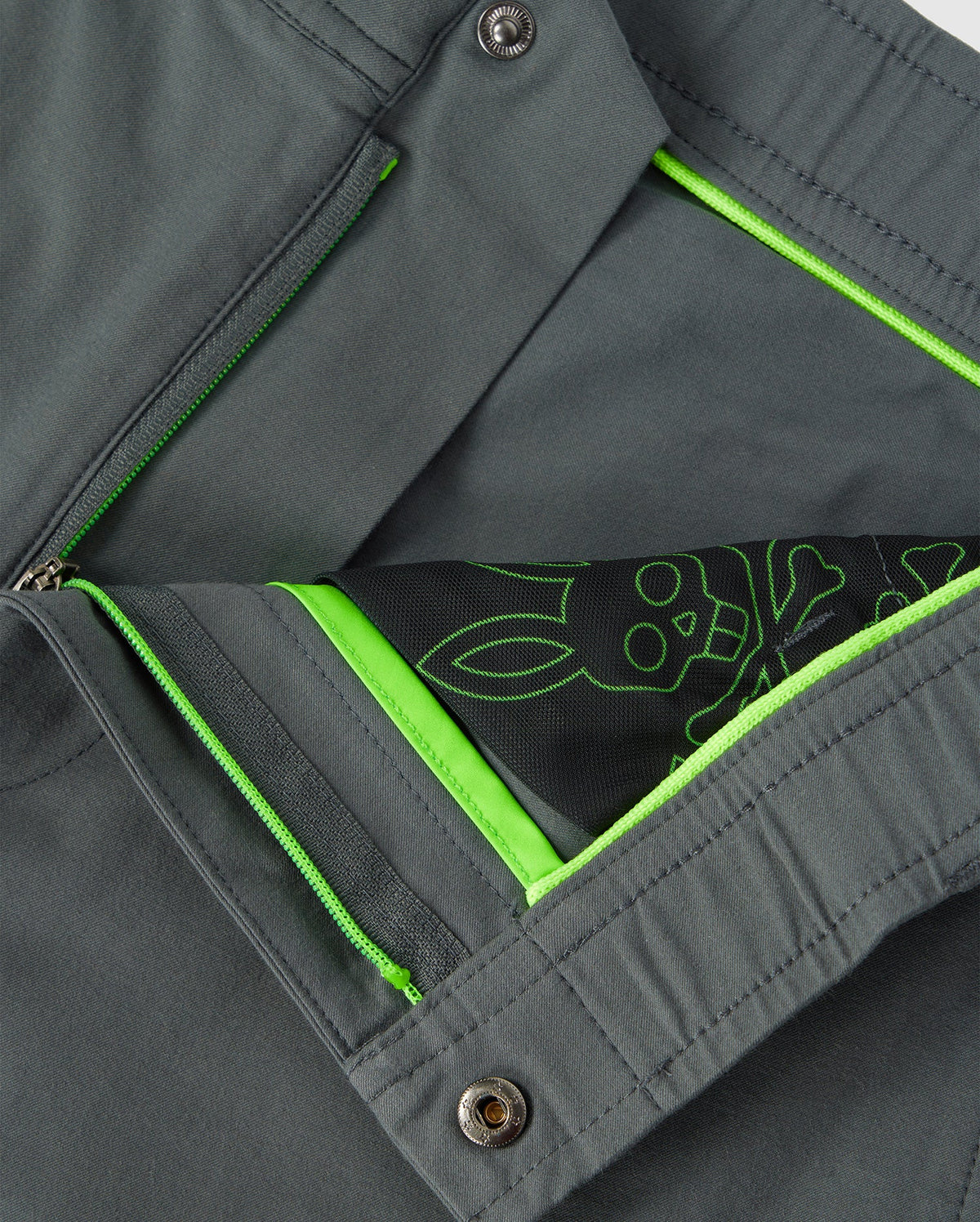 Close-up of a Psych Bunny MENS MADISON COMMUTER PANT - B6P395Z1WB showing interior detail with a neon green zipper and lining, and a decorative sketch of flower and leaves in white on a stretch woven material background.