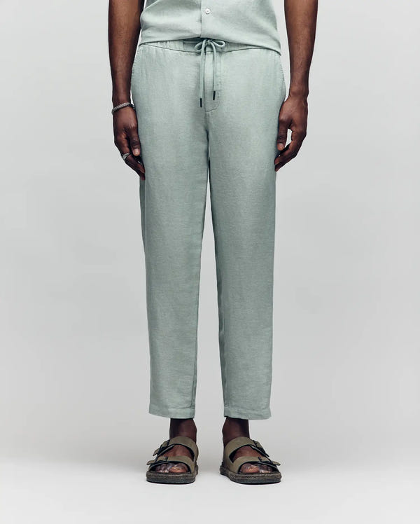 Psycho Bunny light green linen pants with a drawstring waist, relaxed fit, and subtle texture, showcasing refined streetwear style.