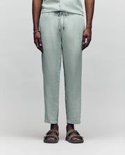 Psycho Bunny light green linen pants with a drawstring waist, relaxed fit, and subtle texture, showcasing refined streetwear style.