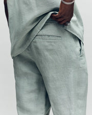 Psycho Bunny light green linen pants with a relaxed fit, visible textured fabric, back pocket, and subtle Psycho Bunny logo embroidery above the back pocket.