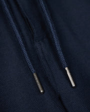 Close-up of navy blue drawstrings with silver metal tips on a dark fabric background, perfect for the Psycho Bunny MENS FATE LINEN DRAWSTRING PANT - B6P471C200. The metal tips have small engraved text, but the content is not fully readable in the image. Ideal for those summer trousers that need both style and durability.