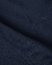 Close-up of the deep navy fabric with a textured surface, reminiscent of the Psycho Bunny MENS FATE LINEN DRAWSTRING PANT - B6P471C200. The material appears to be folded, creating visible creases and shadows that add depth to the image.