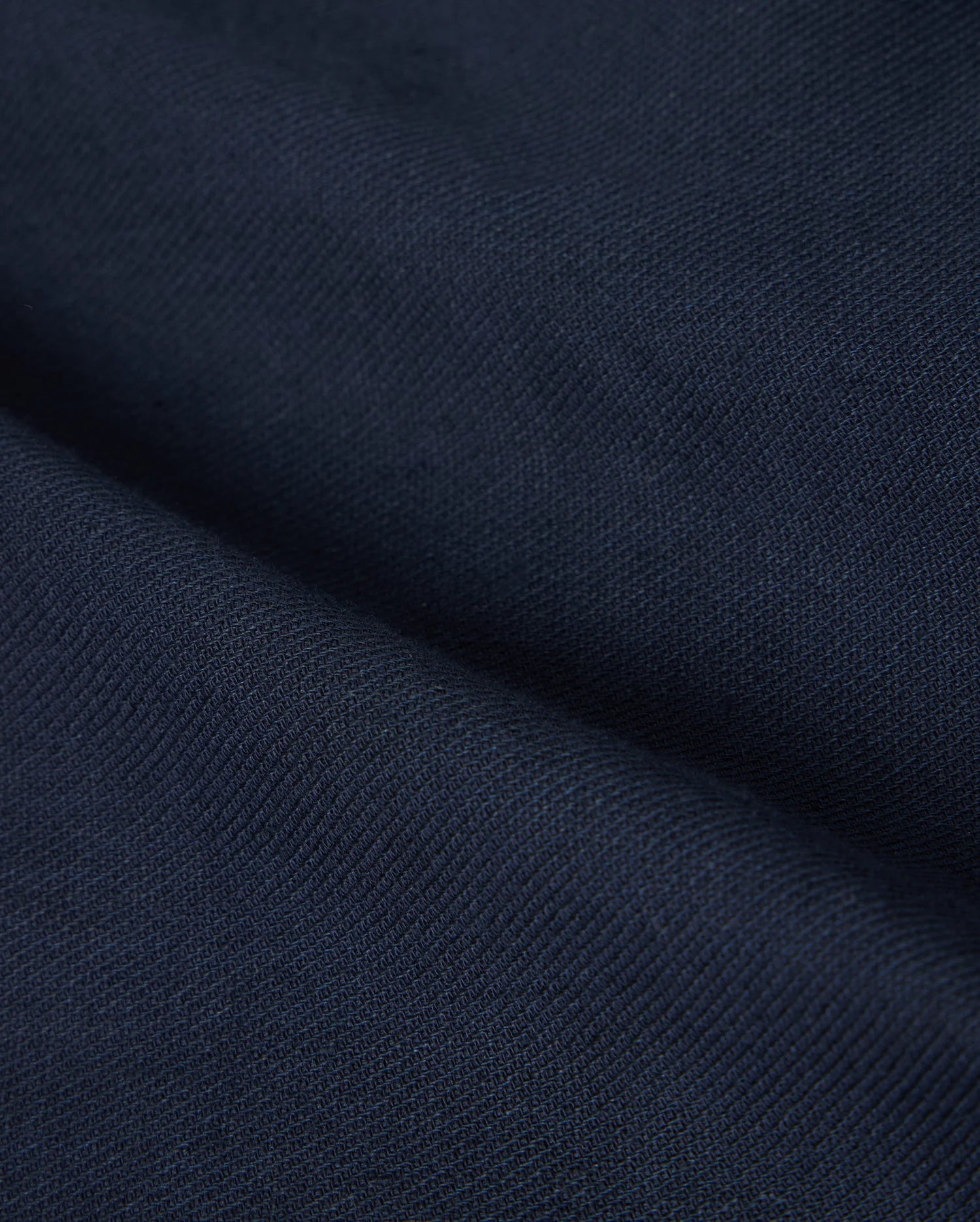 Close-up of the deep navy fabric with a textured surface, reminiscent of the Psycho Bunny MENS FATE LINEN DRAWSTRING PANT - B6P471C200. The material appears to be folded, creating visible creases and shadows that add depth to the image.