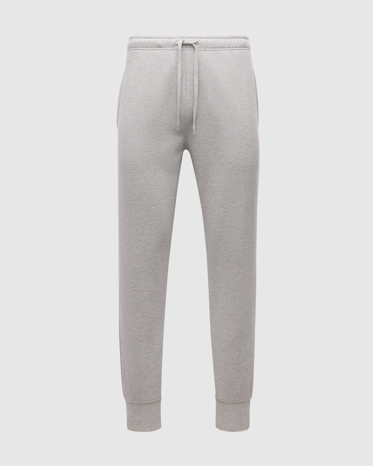The MENS VAL WAFFLE LOUNGE PANT by Psycho Bunny, SKU B6P673E200, are showcased against a plain white background. These gray pants for men come with a drawstring waistband and elastic cuffs, made from soft pima cotton that offers a relaxed fit, perfect for casual or athletic wear.