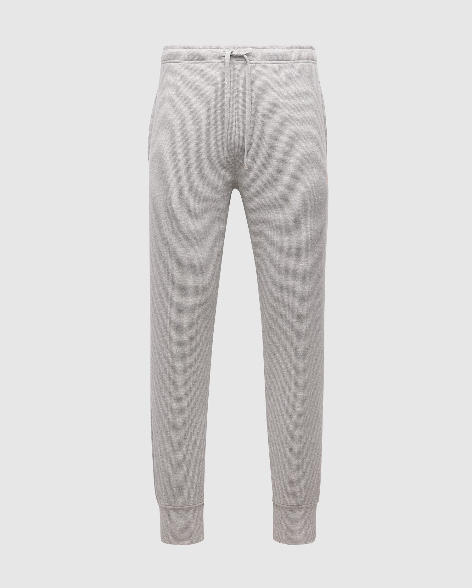 The MENS VAL WAFFLE LOUNGE PANT by Psycho Bunny, SKU B6P673E200, are showcased against a plain white background. These gray pants for men come with a drawstring waistband and elastic cuffs, made from soft pima cotton that offers a relaxed fit, perfect for casual or athletic wear.