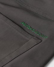 Close-up image of dark gray fabric with visible stitching and the words "Psycho Bunny" embroidered in green thread, showcasing the exceptional quality of our MENS 10K STEP PANT - B6P788D200's four-way stretch material.