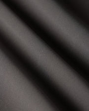 Close-up of smooth, dark grey fabric with soft, diagonal folds creating light and shadow contrast. The texture appears fine and slightly reflective, reminiscent of the luxurious material used in Psycho Bunny's versatile MENS 10K STEP PANT - B6P788D200.