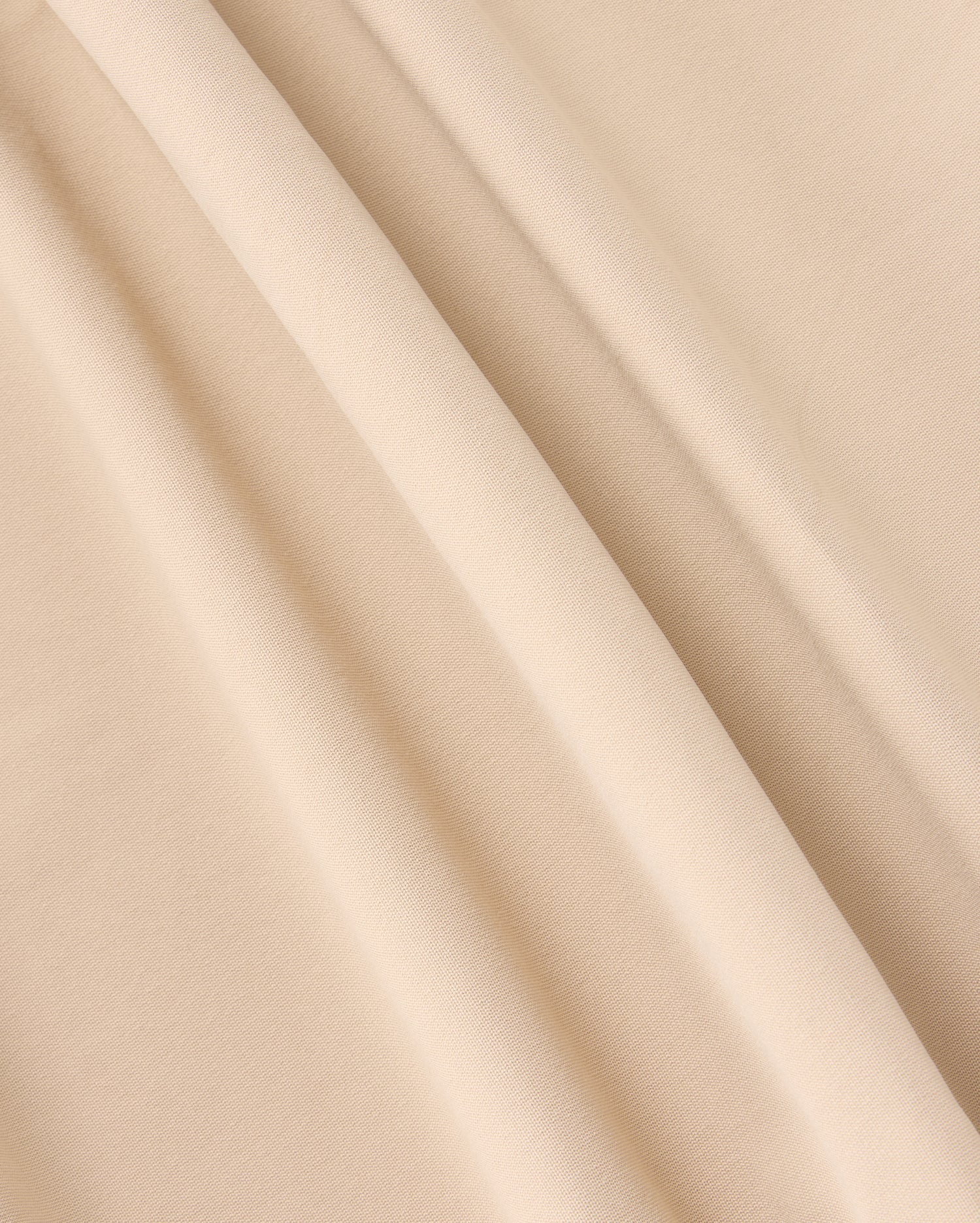 A close-up of beige fabric with a smooth texture and gentle folds creating soft shadows. The material appears lightweight with a plain weave, ideal for crafting the versatile MENS 10K STEP PANT - B6P788D200 by Psycho Bunny, featuring its stylish five-pocket design.
