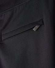 Close-up image of Psycho Bunny's MENS WALTER LIGHTWEIGHT SWEATPANT - B6P860D200 in black, showcasing a zippered side pocket with a small triangular metal tag attached to the zipper. The fabric has a smooth and slightly stretchy texture, ideal for a lightweight sweatpant that blends casual wear with a modern silhouette.