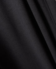 A close-up view of the black fabric material featured in Psycho Bunny's MENS WALTER LIGHTWEIGHT SWEATPANT - B6P860D200. The image captures smooth, uniform folds and a soft texture, with subtle shadows and highlights created by the draping. This indicates a lightweight and slightly glossy fabric that is perfect for casual wear or achieving a breathable fit in your favorite sweatpants.