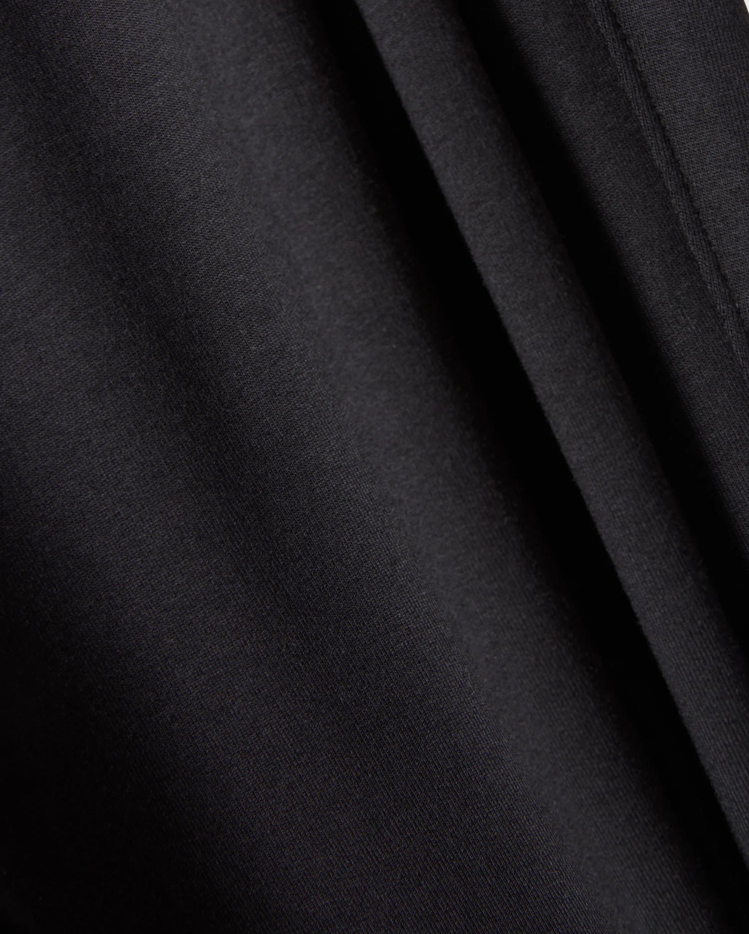 A close-up view of the black fabric material featured in Psycho Bunny's MENS WALTER LIGHTWEIGHT SWEATPANT - B6P860D200. The image captures smooth, uniform folds and a soft texture, with subtle shadows and highlights created by the draping. This indicates a lightweight and slightly glossy fabric that is perfect for casual wear or achieving a breathable fit in your favorite sweatpants.