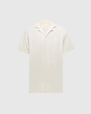 Displayed against a plain background, the Psycho Bunny MENS BRYAN CAMP COLLAR SHORT SLEEVE SHIRT - B6Q581F200 in light beige features a smooth Pima cotton texture, moisture-wicking properties, and a simple design with front buttons.