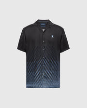 The MENS BENDIGO TENCEL SHIRT - B6Q627F200 by Psycho Bunny is a black short-sleeve shirt with an ombre blue hexagon pattern, made from soft Tencel fabric. It features a camp collar and a small embroidered logo on the chest against a plain white background.