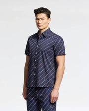 A person is wearing Psycho Bunny's MENS RENMARK STRETCH POPLIN WOVEN SHIRT with matching pants, both featuring a diagonal stripe pattern against a plain white background.
