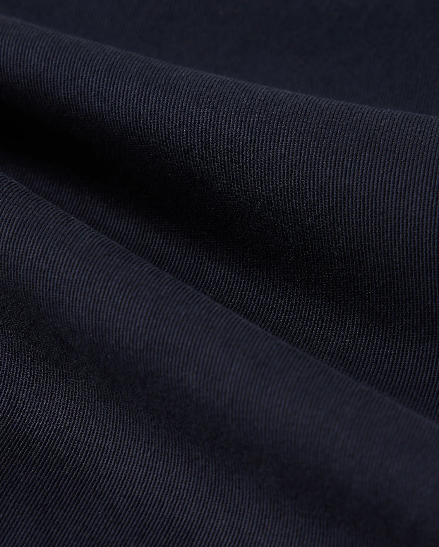 Close-up of a dark blue fabric texture showing detailed weaves and light variations across the surface of Psycho Bunny MENS WILLIS STRETCH TENCEL SHORT - B6R239Y1WB.