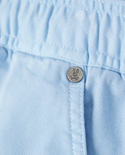 Close-up of a Psycho Bunny light blue corduroy garment with a detailed metal button featuring a small embroidered logo.