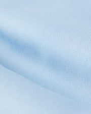 Close-up view of a light blue Psycho Bunny Mens Willis Stretch Tencel Short fabric texture showing fine knit details, slight variations in shade, and an embroidered logo.