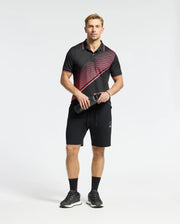 A man in Psycho Bunny's black and red patterned polo shirt made of a cotton-blend jersey and MENS DACANO PERFORATED SWEATSHORT stands holding a water bottle. He has an athletic fit, wearing sleek black running shoes and socks against a white background.