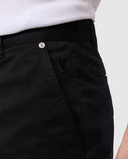 Close-up view of a person wearing black Psycho Bunny men's York chino shorts, featuring a small embroidered logo near the pocket with a visible branded button on the waistband.