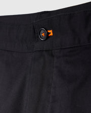 Close-up of a black trouser waistband featuring a button with an orange starburst design, emphasizing detail and texture in Psycho Bunny's Men's York Chino Shorts.