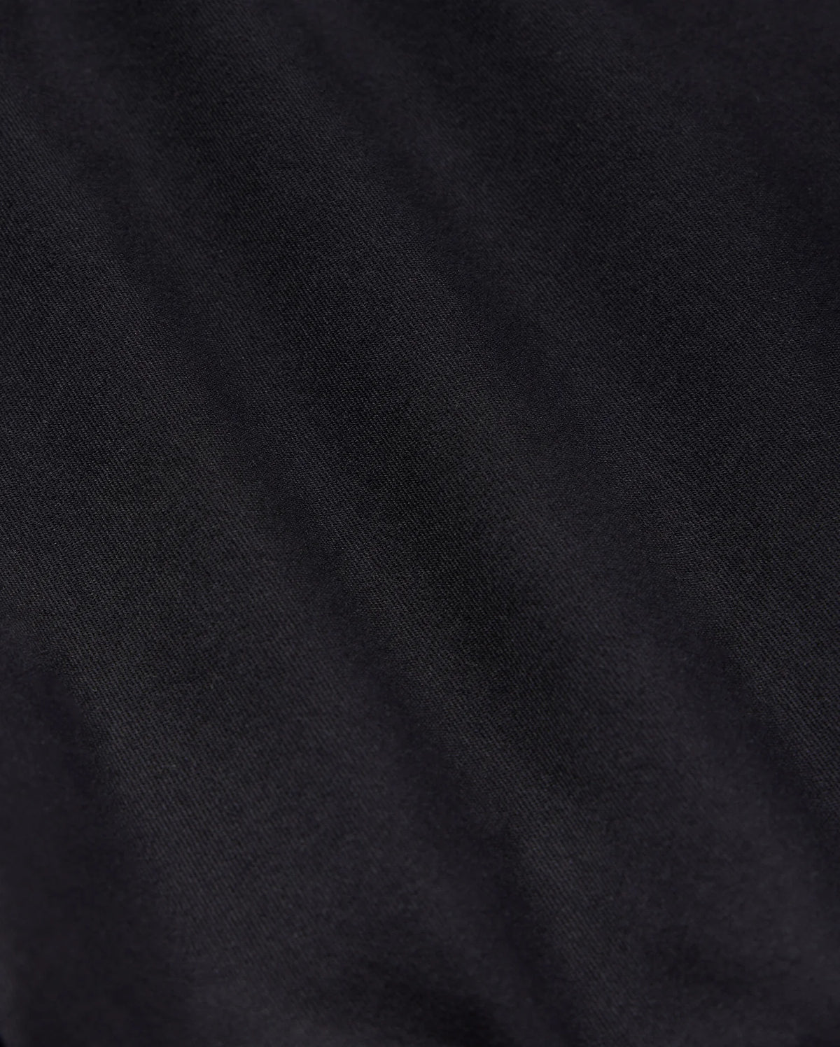 Close-up detail of a textured black fabric, suitable for Psycho Bunny's MENS YORK CHINO SHORT - B6R357B200, showing subtle variations in shading and the intricacies of the weave pattern.