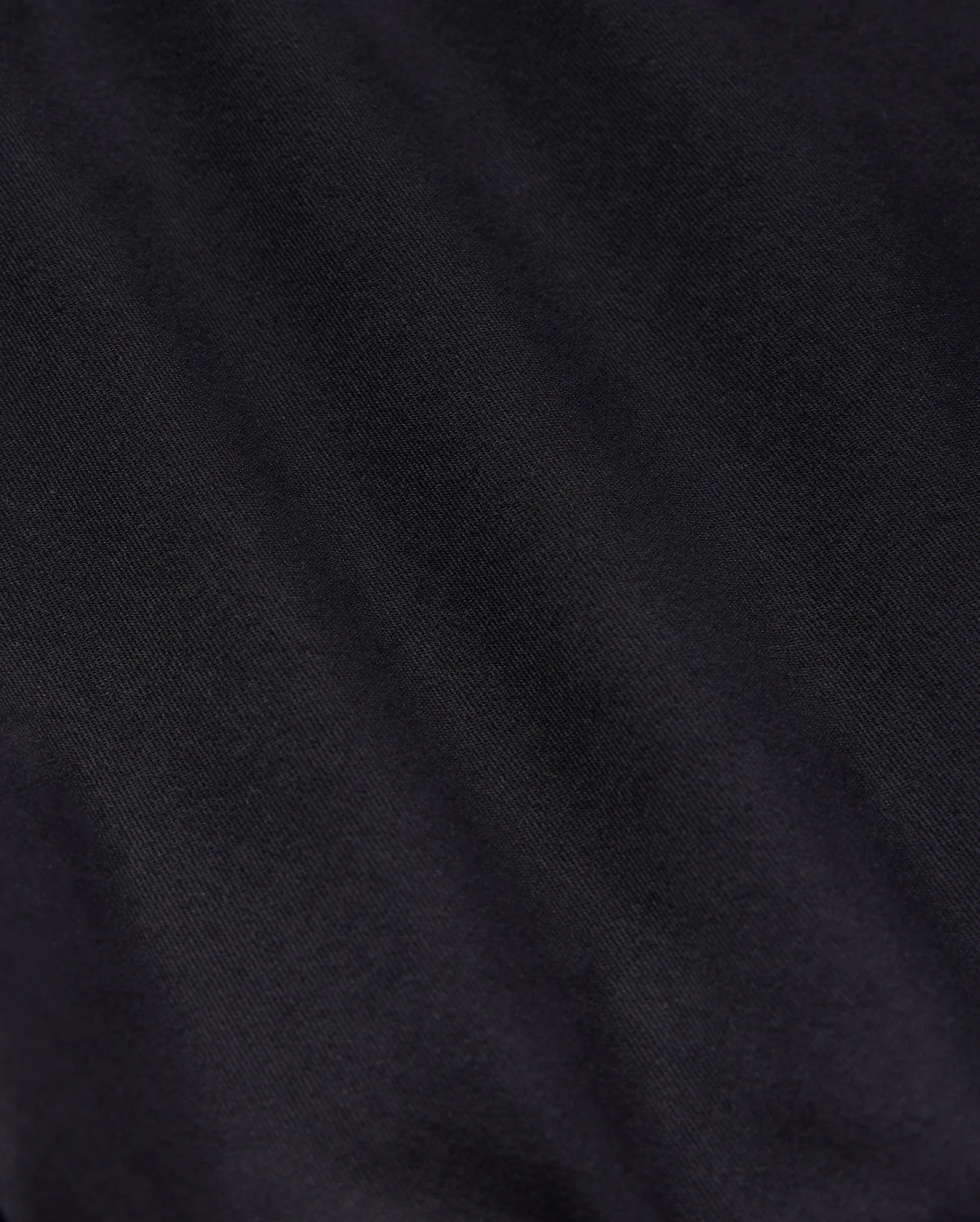 Close-up detail of a textured black fabric, suitable for Psycho Bunny's MENS YORK CHINO SHORT - B6R357B200, showing subtle variations in shading and the intricacies of the weave pattern.