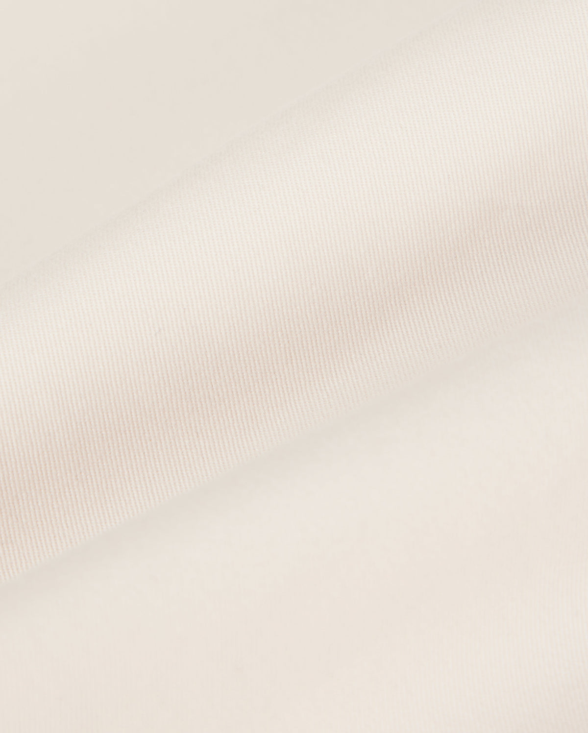 Close-up of a beige Psycho Bunny MEN'S YORK CHINO SHORT - B6R357B200 fabric with a smooth texture, showing a folded edge lying against a plain, soft background.