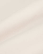 Close-up of a beige Psycho Bunny MEN'S YORK CHINO SHORT - B6R357B200 fabric with a smooth texture, showing a folded edge lying against a plain, soft background.
