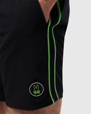 Close-up of a person wearing Psycho Bunny MENS SONTERRA STRIPE SPORT SHORT - B6R464C200 with light green piping along the side seam. The quick-drying shorts feature a patch with a green bunny logo near the hem. The person's hand is partially visible inside the pocket, showcasing the breathable fabric.