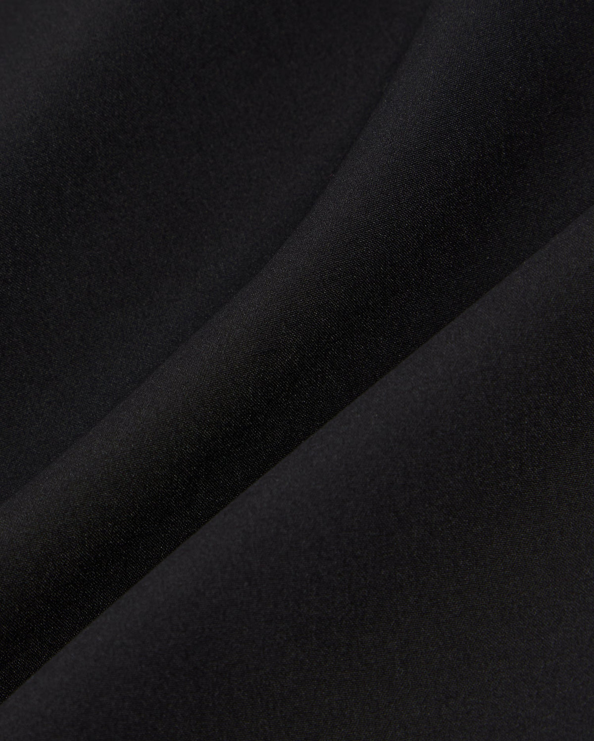 Close-up of a smooth, black fabric showing subtle light reflections and a gentle fold. The texture appears soft and even, indicating a fine, high-quality material often used in the Psycho Bunny MENS SONTERRA STRIPE SPORT SHORT - B6R464C200 for its quick-drying and breathable properties.
