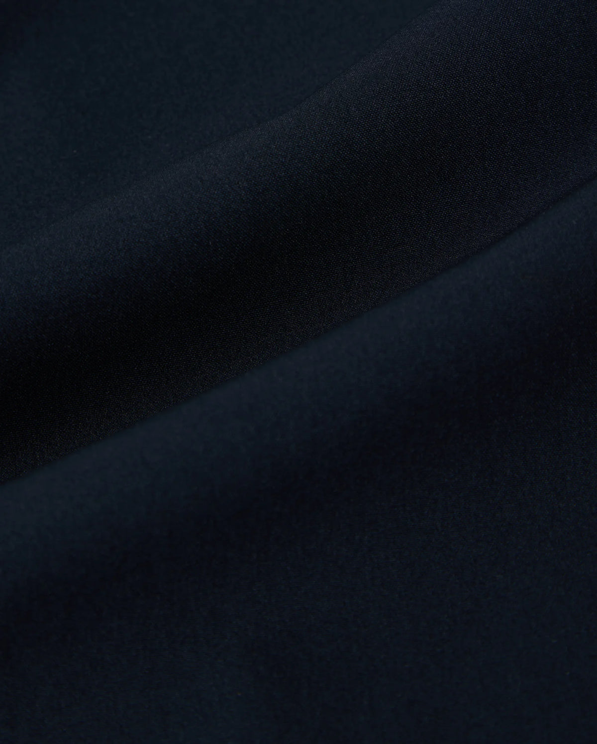 Close-up of dark blue fabric with soft, smooth texture and gentle folds. The material appears to be finely woven, creating a uniform and seamless appearance. Its quick-drying properties make it ideal for the Psycho Bunny MENS SONTERRA STRIPE SPORT SHORT - B6R464C200.