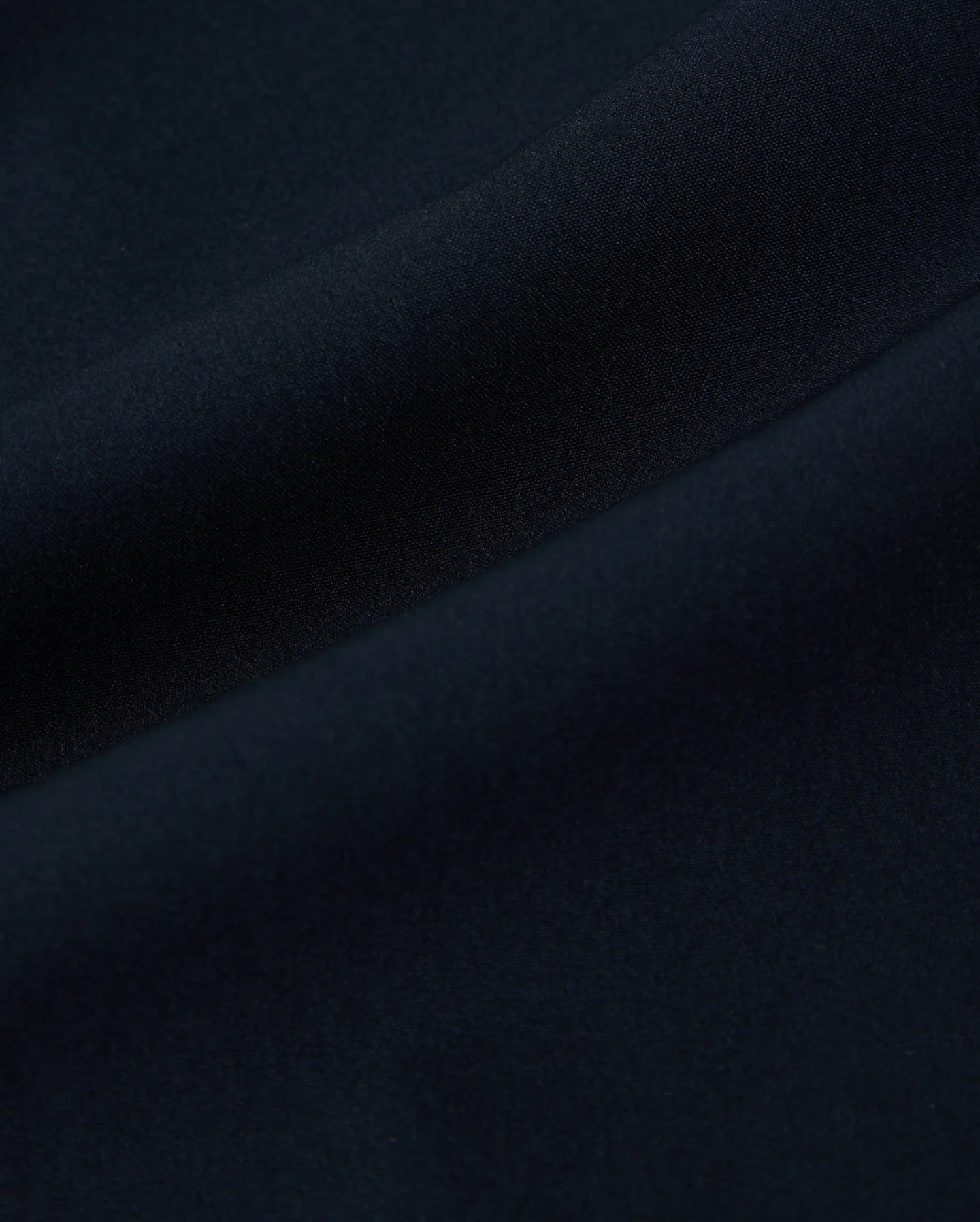 Close-up of dark blue fabric with soft, smooth texture and gentle folds. The material appears to be finely woven, creating a uniform and seamless appearance. Its quick-drying properties make it ideal for the Psycho Bunny MENS SONTERRA STRIPE SPORT SHORT - B6R464C200.