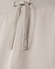 Close-up of the MENS WALTER LIGHTWEIGHT SWEATSHORT - B6R477D200 by Psycho Bunny, showcasing the waistband and tied drawstrings. The fabric, a high-quality cotton blend, appears soft and slightly textured, with metal grommets through which the drawstrings are threaded. The stitching along the regular fit waistband is visible.
