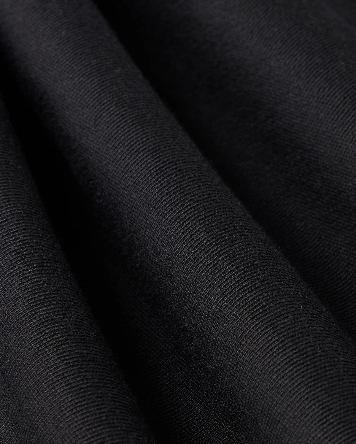 Close-up view of a black fabric with fine, visible texture and folds creating subtle shadows and highlights, depicting the material's softness and smooth surface—ideal for Psycho Bunny's MENS LEVY FLEECE SWEATSHORT - B6R862D200.
