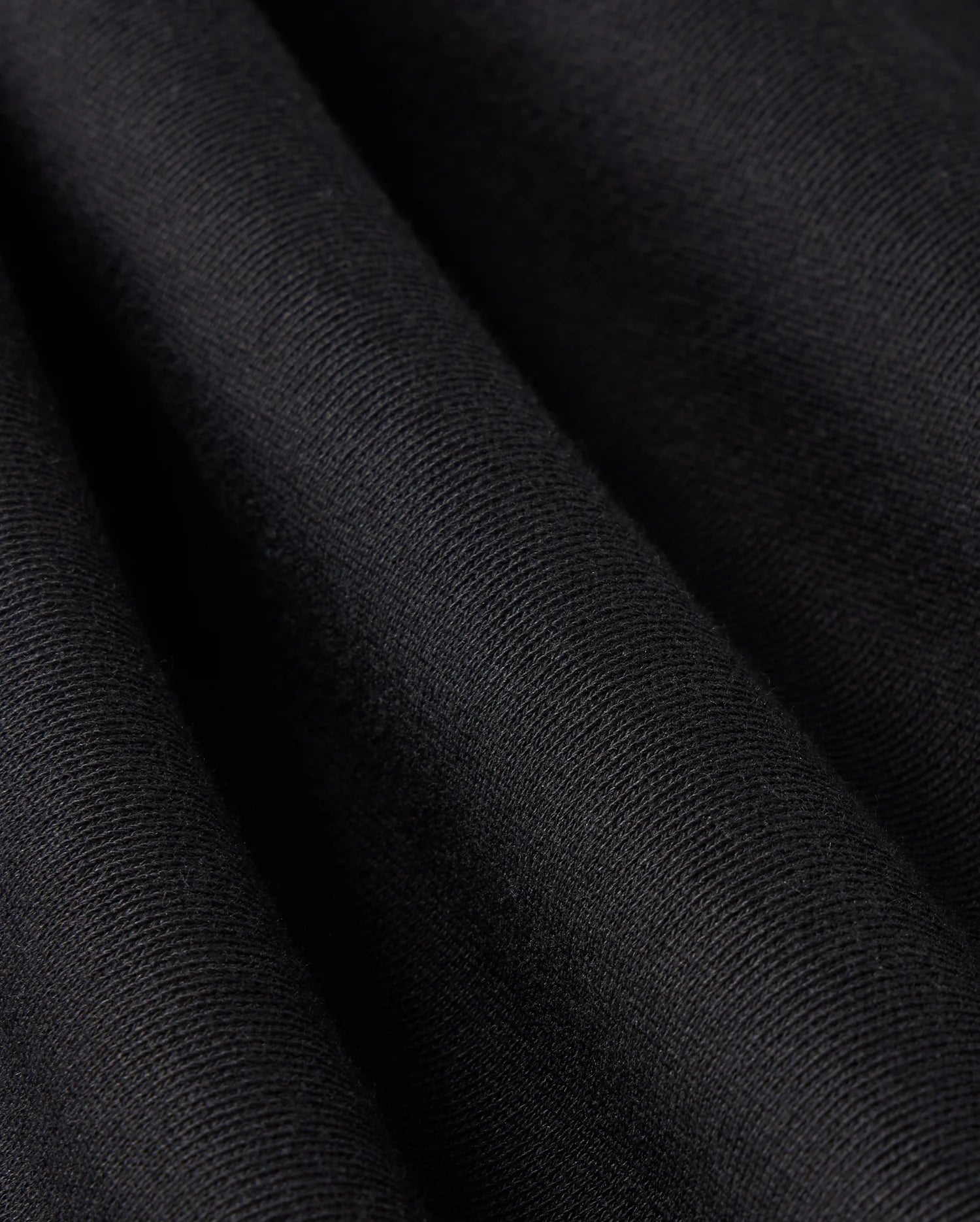 Close-up view of a black fabric with fine, visible texture and folds creating subtle shadows and highlights, depicting the material's softness and smooth surface—ideal for Psycho Bunny's MENS LEVY FLEECE SWEATSHORT - B6R862D200.