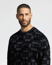 A man with short hair and a beard is wearing the stylish MENS ROMEO LIGHTWEIGHT SWEATSHIRT - B6S129E200 by Psycho Bunny. The black crew sweatshirt features "Psycho Bunny" and bunny logos, as he gazes directly at the camera against a neutral background, exuding confident simplicity.