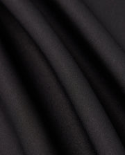 Close-up of the Psycho Bunny MENS LAURIER 1/4 ZIP HOODIE - B6S149D200 in black, crafted from cotton jersey fabric with soft, flowing folds and a smooth texture. The hoodie exudes an elegant, slightly reflective quality, embodying an athleisure aesthetic as it captures light along its gentle curves.