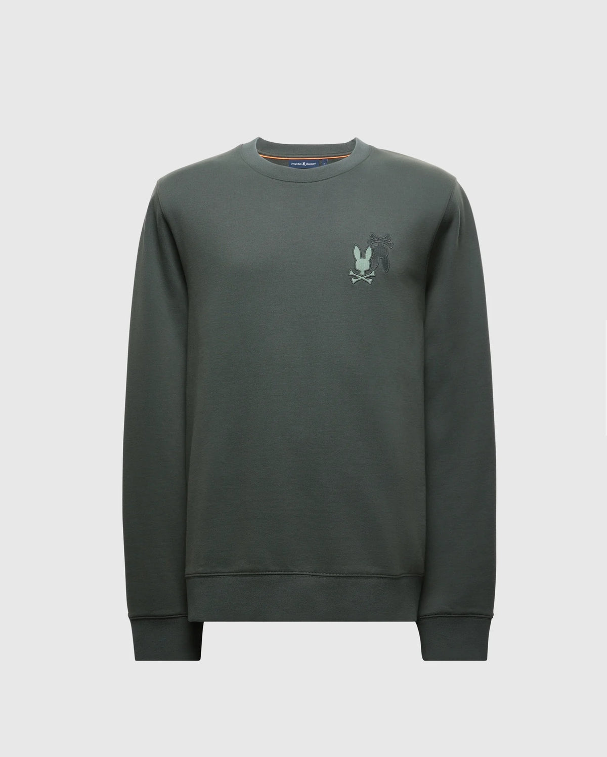 The MENS WORDMARK PEACHED TERRY CREW by Psycho Bunny (B6S278E200) is a dark green pullover made from knit cotton. It features a subtle graphic design on the left chest with a stylized silhouette of a character. With long sleeves and a relaxed fit, this crewneck sweatshirt is ideal for casual style with comfort.