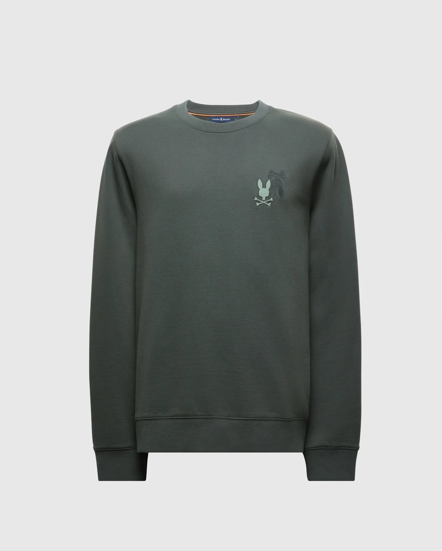 The MENS WORDMARK PEACHED TERRY CREW by Psycho Bunny (B6S278E200) is a dark green pullover made from knit cotton. It features a subtle graphic design on the left chest with a stylized silhouette of a character. With long sleeves and a relaxed fit, this crewneck sweatshirt is ideal for casual style with comfort.