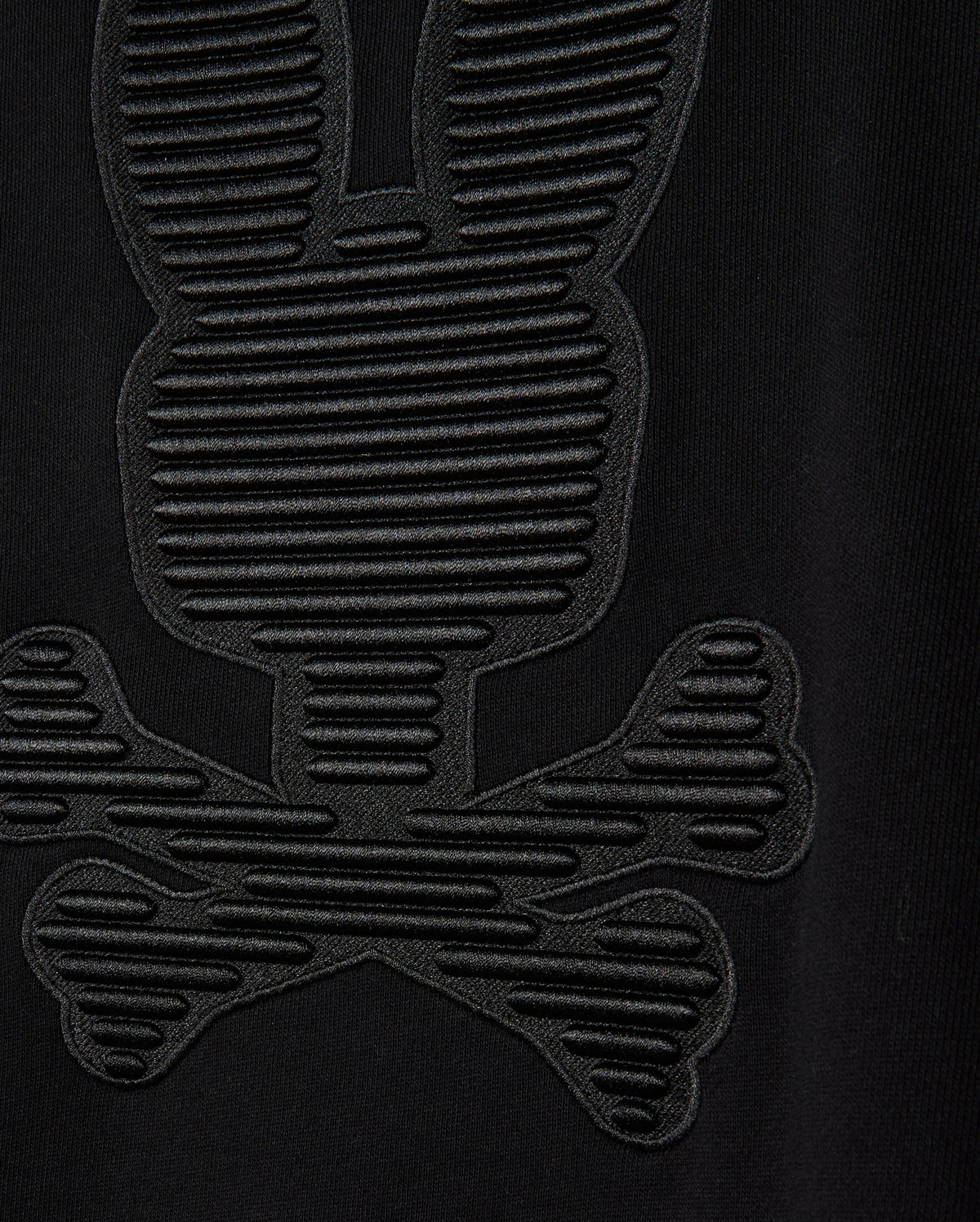 Close-up of the MENS KINGSTON SWEATSHIRT - B6S480D200 by Psycho Bunny, showcasing a lush cotton jersey fabric with an embossed pattern that resembles a cartoonish skull and crossbones adorned with bunny ears. This design, evocative of the Kingston 3D-embroidery sweatshirt styles, is crafted with textured, raised lines.