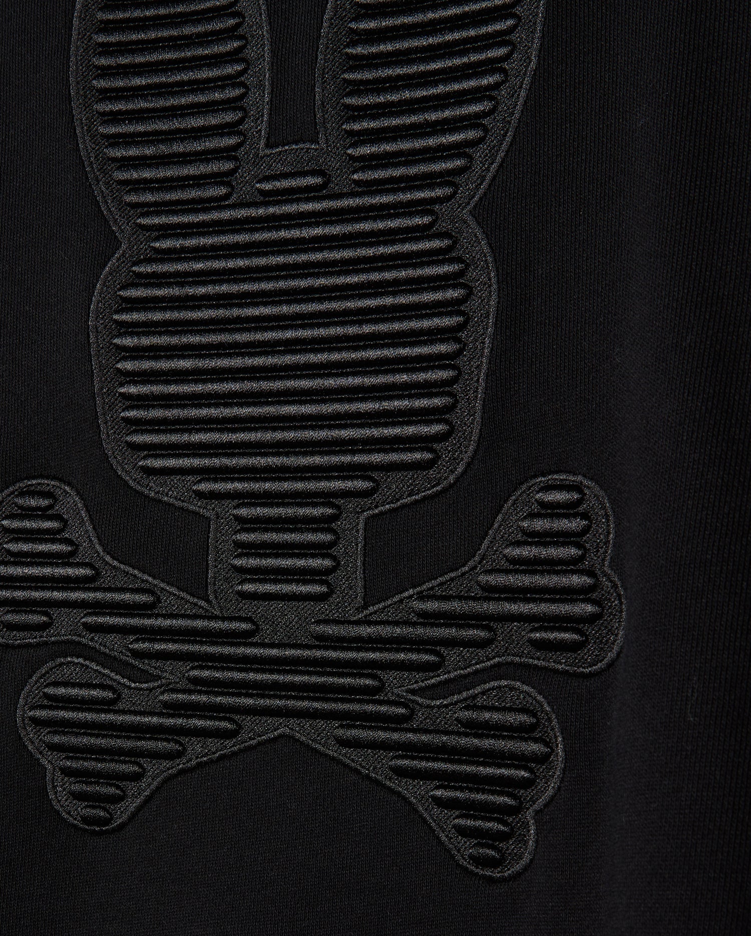 Close-up of the MENS KINGSTON SWEATSHIRT - B6S480D200 by Psycho Bunny, showcasing a lush cotton jersey fabric with an embossed pattern that resembles a cartoonish skull and crossbones adorned with bunny ears. This design, evocative of the Kingston 3D-embroidery sweatshirt styles, is crafted with textured, raised lines.