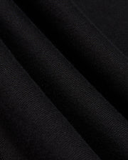 A close-up of the folded fabric reveals its textured and soft surface, evoking the feel of a premium cotton jersey. The black material appears smooth with a slight ribbed effect, and the gentle folds create subtle shadows and depth. This expertly crafted fabric is part of the Psycho Bunny MENS KINGSTON SWEATSHIRT (B6S480D200), showcasing intricate 3D embroidery details.