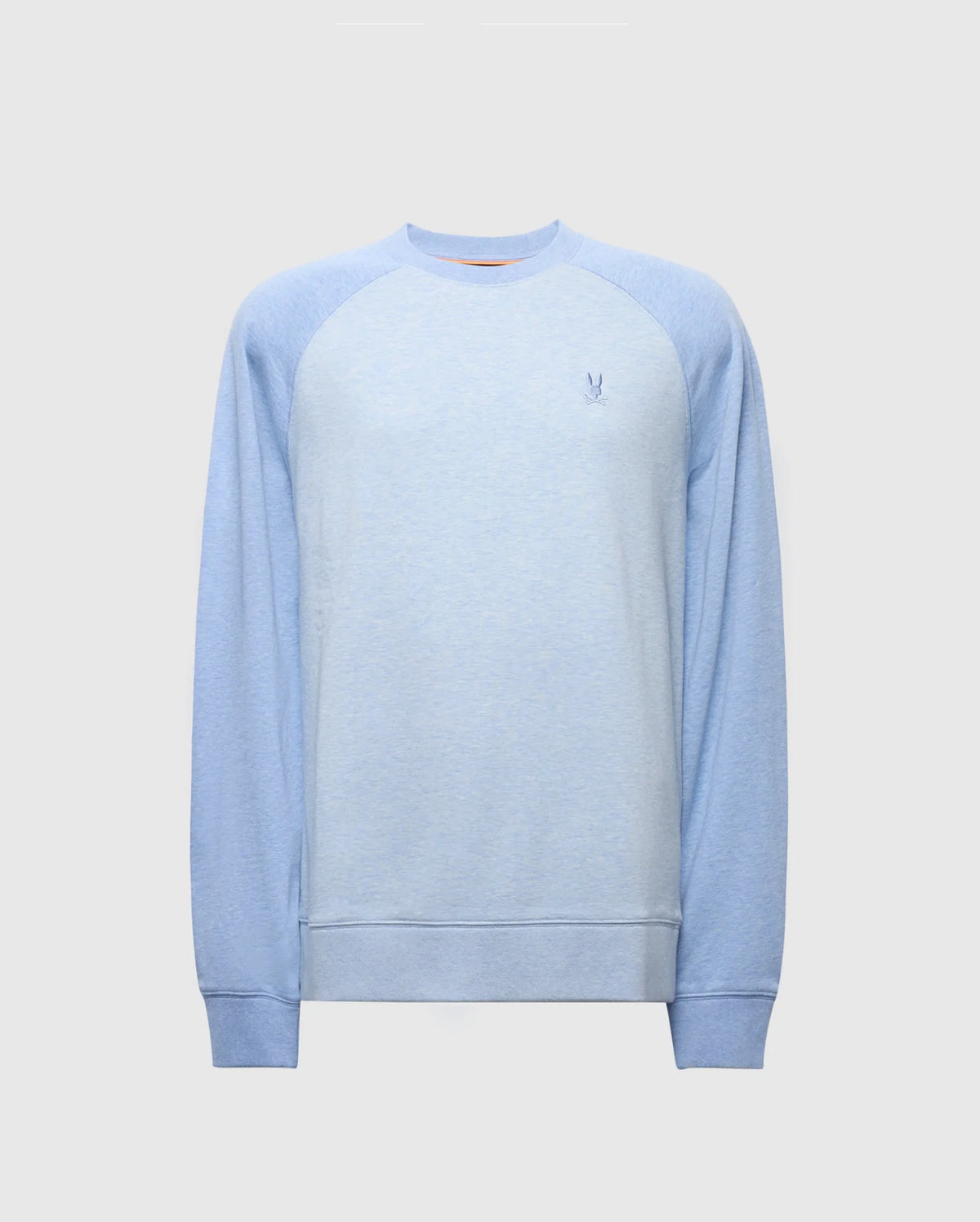 The Psycho Bunny MENS ARCHIE SWEATSHIRT - B6S630F200 is a light blue cotton jersey with faded raglan sleeves and a small embroidered Bunny logo on the chest. It features ribbed cuffs and hem, perfect for monochrome styling against a plain light gray background.