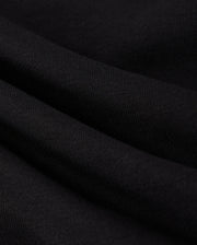 A close-up image reveals the black fabric of the MENS COURTSIDE SWEATSHIRT - B6S688C200 by Psycho Bunny, showcasing a soft, slightly wavy texture with a visible weave pattern. The smooth and stretchy material features subtle shadows that enhance its folds, offering a tennis-inspired elegance reminiscent of its design.