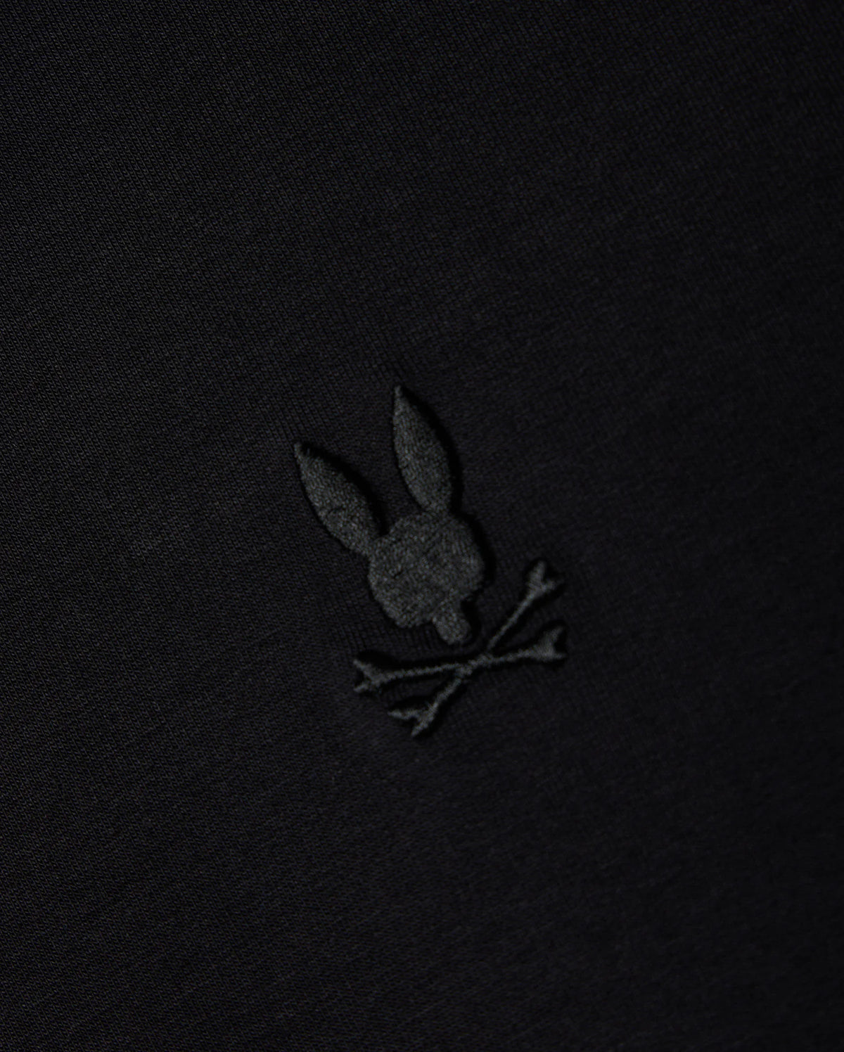 The MENS DUKE EMBROIDERED SWEATSHIRT - B6S706D200 from Psycho Bunny is crafted in a high-quality cotton-blend and showcases a black fabric with an intricately embroidered bunny skull and crossed bones. This elegant monochromatic design enhances the pullover's blend of sophistication and edginess, making it ideal for a refined yet bold style.