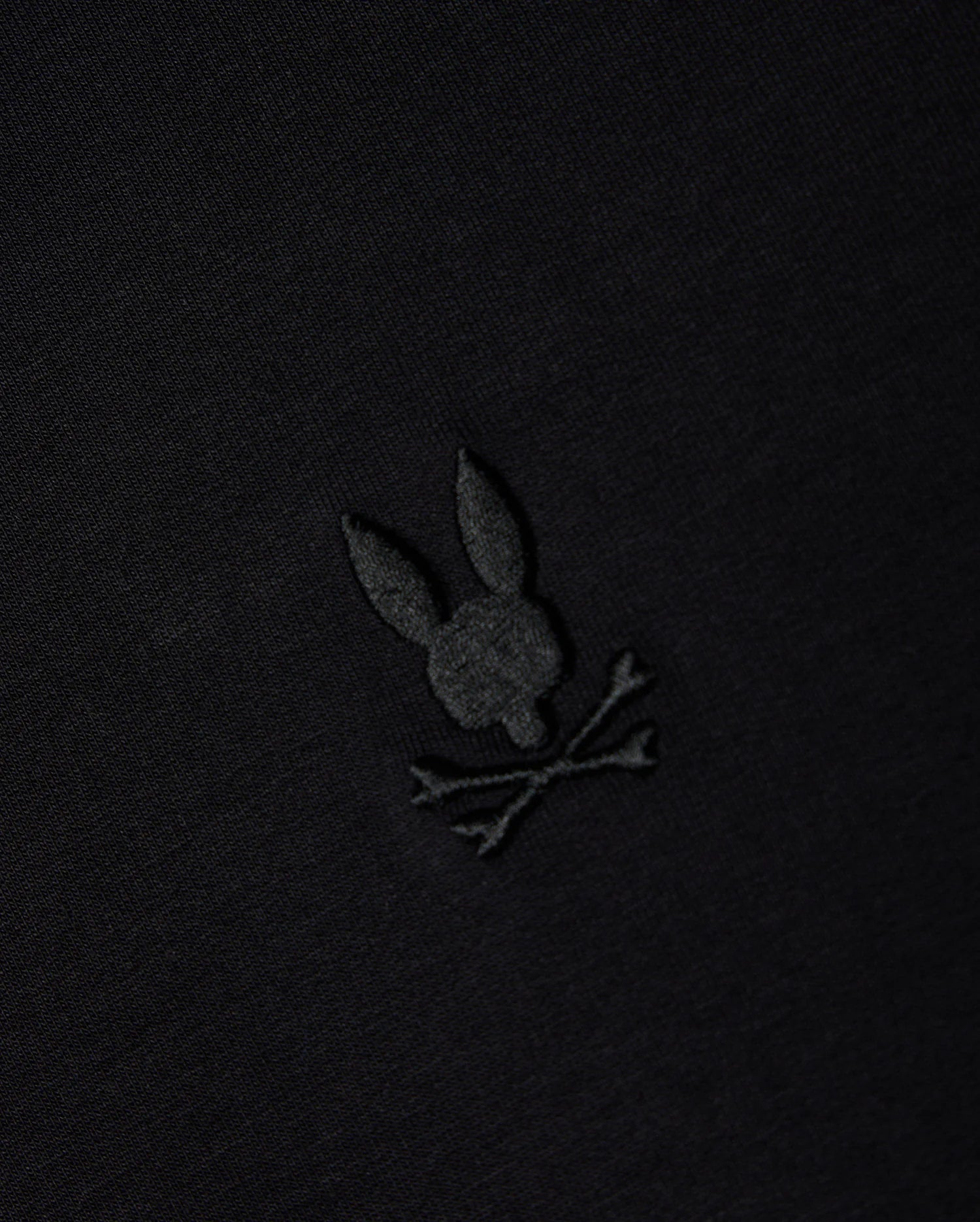 The MENS DUKE EMBROIDERED SWEATSHIRT - B6S706D200 from Psycho Bunny is crafted in a high-quality cotton-blend and showcases a black fabric with an intricately embroidered bunny skull and crossed bones. This elegant monochromatic design enhances the pullover's blend of sophistication and edginess, making it ideal for a refined yet bold style.