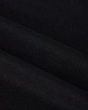 Close-up of the MENS DUKE EMBROIDERED SWEATSHIRT - B6S706D200 from Psycho Bunny, featuring a black cotton-blend fabric with a smooth texture and subtle diagonal folds. The image emphasizes the sweatshirt's dark, uniform color and soft, even surface reminiscent of luxury apparel.