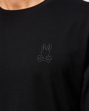 Close-up of the Psycho Bunny MENS ALBERTON LONG SLEEVE TEE - B6T867D200 in black, a true fashion masterpiece made from fine Pima cotton. It features an intricate dark embroidered design of a bunny head with crossed bones below it on the left side of the chest.