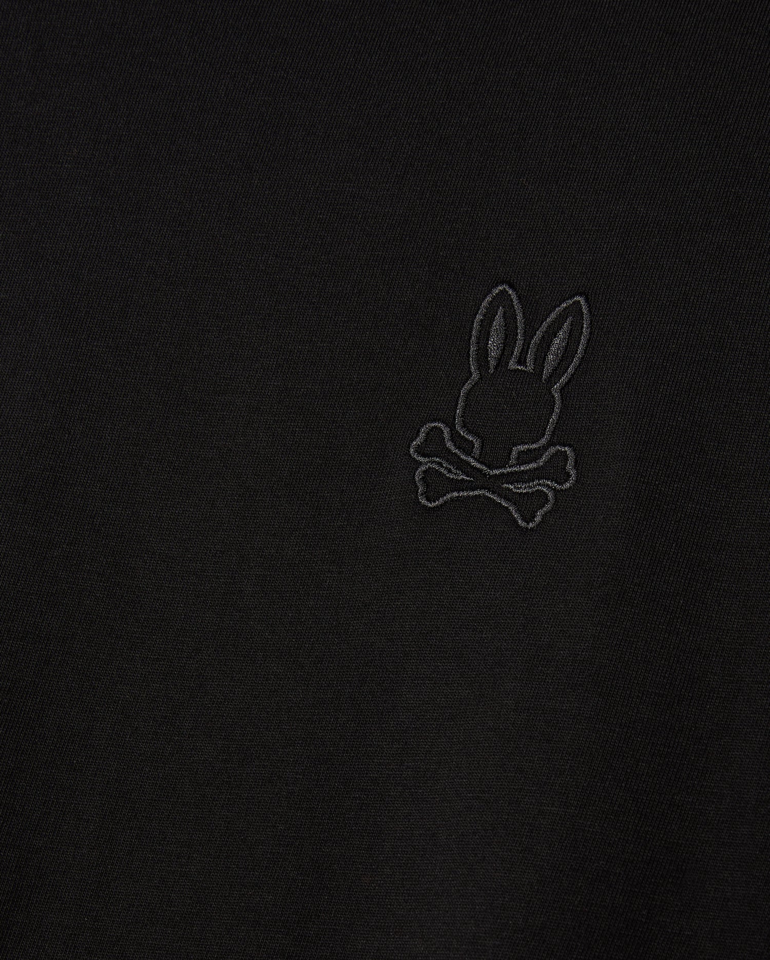 Introducing the MENS ALBERTON LONG SLEEVE TEE - B6T867D200 by Psycho Bunny, featuring a detailed embroidered design of a bunny with crossed bones beneath. This black fabric tee is crafted from premium Pima cotton, delivering both a stylish appearance and luxurious comfort.