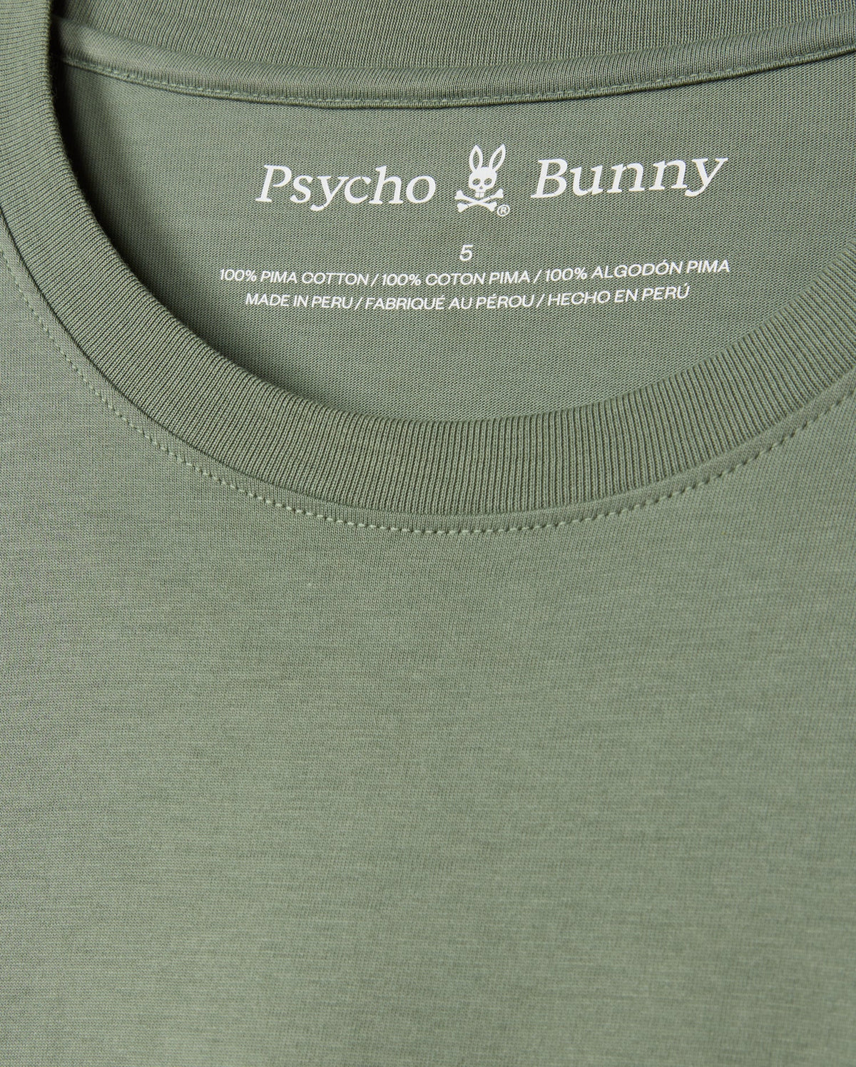Close-up of the MENS ALBERTON LONG SLEEVE TEE - B6T867D200 in vibrant green, prominently displaying the Psycho Bunny label along with a small bunny logo. The label details the size and confirms that it is made from 100% Pima cotton, crafted in Peru—a true fashion masterpiece.